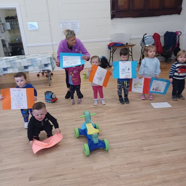 toddlers holding up posters that they've coloured in